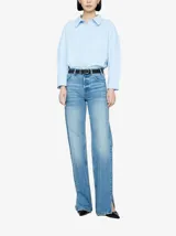 Pantalón de jean celeste, de corte recto, tiro alto y con aberturas en los tobillos.