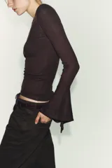 Camiseta de cuello redondo y manga larga, confeccionada en tejido rib con mezcla de lyocell. Presenta un diseño ajustado con terminación de volantes en los puños y bajo recto.