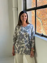 Sweater de punto con estampado de manchas irregulares, cuello en V y mangas largas con puños ajustados.