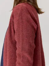 Saco abierto de punto con textura jaspeada en color gris oscuro, con bordes frontales en contraste color marrón. Presenta mangas largas y un corte recto.