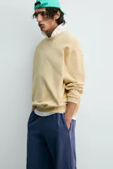 Sudadera de algodón con interior rizo, cuello redondo y manga larga. Presenta un efecto lavado que le da un color amarillo pálido y un estampado frontal en hilo blanco con el texto "west nord 89".