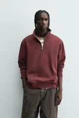 Sudadera roja de corte regular, con cuello alto y cierre frontal de cremallera. Manga larga y terminaciones en rib.