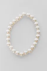 Correa para celular compuesta por una cadena de perlas sintéticas blancas, diseñada para sujetar y decorar el dispositivo.