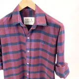 Camisa de franela a cuadros color uva con azul, de manga larga y corte clásico. Tiene cuello italiano y logo bordado en el pecho.