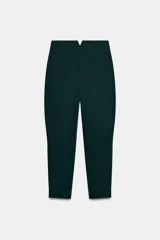 Pantalón de tiro alto color verde oscuro, confeccionado en mezcla de algodón. Presenta bolsillos laterales, detalle de tejido con volumen y costuras torcidas. Cierre frontal con cremallera, botón interior y ganchos metálicos ocultos.