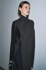 Chaleco de punto confeccionado en mezcla de lana, con cuello subido, diseño sin mangas y aberturas laterales con detalle de lazos.