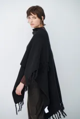 Ruana de tejido de punto en color negro, con diseño de cuello alto y terminaciones con flecos en los bordes.
