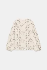 Blusa color crudo con bordados florales en azul oscuro. Presenta cuello redondo con escote pico ajustable mediante cordones con terminaciones de cuentas de madera, y mangas largas abullonadas con puños elásticos.