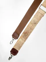 Correa ajustable para cartera confeccionada en cuero, con diseño pintado a mano en tono beige con textura moteada y reverso en cuero liso color marrón. Incluye herrajes metálicos plateados.
