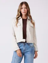 Chaqueta color beige de símil gamuza, con cuello solapa, cierre frontal y bolsillos aplicados en el pecho. Puños con botón a presión.