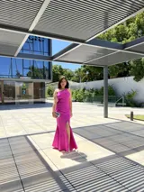 Vestido largo de fiesta color fucsia, de corte sirena, con un solo hombro y abertura lateral.