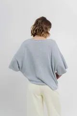 Sweater oversize de tejido liviano color blanco roto, con textura semi traslúcida, escote redondo y mangas amplias estilo murciélago.