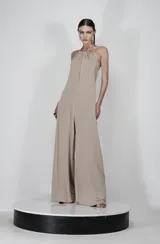 Mono largo color beige de jersey, con escote halter con detalle de herrajes metálicos plateados y pierna ancha.