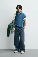 Polo de algodón con estructura piqué, color azul deslavado. Presenta un corte regular fit, cuello solapa con cierre de botones, manga corta con acabado en rib y bajo asimétrico con aberturas laterales.