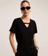 Blusa negra de manga corta confeccionada en crepé, con escote en V y una tira horizontal con hebilla metalizada en la parte superior del escote.