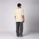 Remera oversized de algodón grueso con textura micropanal, color beige, de cuello redondo y manga corta, con costura decorativa en "X" en el escote y diseño liso sin logos.