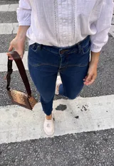 Pantalón de jean azul oscuro, corte recto, tiro alto y detalles de costuras en la parte superior.