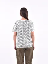 Remera de manga corta color beige con estampado de bananas en tonos amarillo, naranja y rosado.