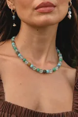 Collar corto de cuentas redondas de piedras naturales en tonos verde, celeste, gris y marrón, separadas por pequeñas piezas metálicas.