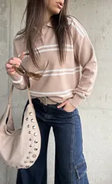 Sweater de punto con rayas horizontales blancas y base en tono beige y rosado, cuello polo con botones y mangas largas.