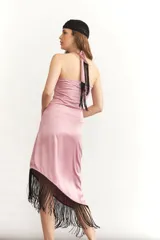 Vestido midi sin mangas color turquesa, con escote strapless y detalle de nudo frontal. El ruedo presenta un corte asimétrico con flecos negros largos.