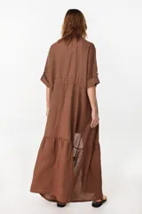 Vestido camisero largo de lino italiano color celeste, de corte relajado, con mangas caídas, jareta ajustable en la cintura, cierre frontal de botones y bajo con volado fruncido.