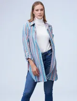 Camisola estampada a rayas verticales en tonos celeste, azul, naranja y marrón. Cuello con solapa, abertura central con botones y bolsillo aplicado en el pecho. Mangas largas regulables con presilla y botón. Laterales con bolsillos en costura. Marca Ruby Rd.