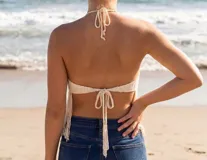 Top de crochet color beige con diseño halter y flecos largos en el ruedo.