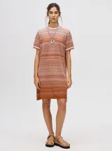 Vestido corto de tejido de punto con efecto degradado, cuello redondo y mangas cortas con puños a rayas en contraste. Presenta un diseño holgado y calado.