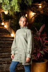 Camisa verde militar de algodón con cuello alto con volado, mangas largas con aberturas y tiras para atar, tablas en la parte inferior y cierre con tres ataduras.