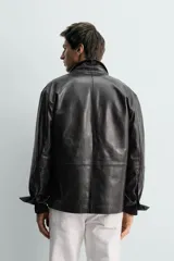 Sobrecamisa de corte regular confeccionada en piel napa negra, con cuello solapa, cierre frontal de botones y mangas largas con puños abotonados.
