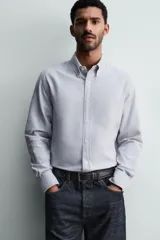 Camisa de corte regular fit confeccionada en tejido de algodón con efecto lavado. Presenta cuello abotonado, manga larga con puños abotonados, bolsillo en el pecho y cierre frontal con botones.
