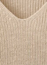 Chaleco de punto grueso color beige, de diseño recto, con cuello en V y manga larga.