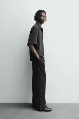 Pantalón de corte relajado confeccionado en tejido fluido con mezcla de lyocell. Presenta cintura elástica ajustable con cordón, bolsillos laterales y un bolsillo trasero de vivo con botón.