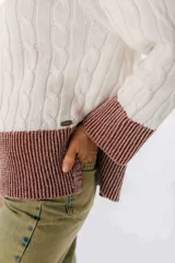 Sweater de punto trenzado color crudo con cuello redondo y terminaciones en azul.