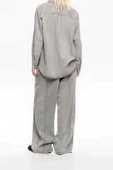 Pantalón jean ancho gris, de tiro bajo, confeccionado en mezcla de lyocell y algodón, con bolsillos delanteros y pespuntes decorativos.