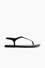 Sandalias planas de dedo color negro, con diseño minimalista y tira fina en el empeine con sujeción trasera elástica.