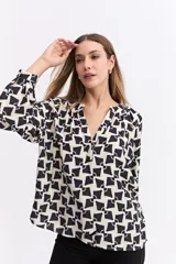 Blusa de corte relajado con estampado geométrico en tonos beige y negro. Presenta cuello en V con detalle de frunces, mangas largas abullonadas con puños elásticos y una caída fluida.