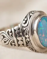 Anillo de plata envejecida con piedra natural ovalada de ópalo en tono celeste y detalles grabados en la banda.
