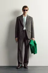 Pantalón de traje regular fit de la colección especial Aaron Levine x Zara, confeccionado en mezcla de lana y lino de color gris. Presenta diseño con pinzas delanteras, bolsillos laterales y traseros de doble vivo con botón, y cierre frontal con cremallera y gancho metálico oculto.