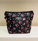 Neceser con cierre superior, estampado floral en tonos rosa y verde sobre fondo negro.