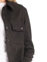 Chaqueta de estilo camisero confeccionada en tejido tipo suede, con cuello clásico, cierre frontal mediante botones a presión y bolsillos aplicados en el pecho. Presenta mangas largas con puños ajustables.