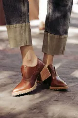 Zapato de cuero color beige, con taco de madera y suela dentada. Presenta un diseño slip-on con detalles de textura en relieve en los laterales y el empeine.