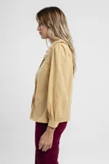 Camisa verde agua con cuello babero con volados, mangas largas abullonadas y cierre frontal con botones.