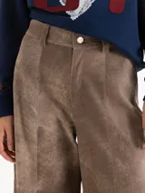 Pantalon de cuero ovino gris con diseño de pata ancha y recortes geométricos a la altura de las rodillas.