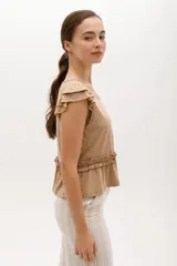 Remera de algodón y lyocell color beige, con cuello redondo, mangas cortas con volados y detalle de frunce con volado en la cintura.