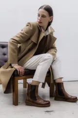 Bota tipo Chelsea de cuero vacuno color suela, con diseño brogue en la puntera y laterales. Presenta paneles elásticos laterales en color marrón oscuro, tirador trasero y suela de goma con plataforma.