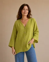 Camisa verde pistacho de lino, con cuello en V, cierre frontal con botones y mangas tres cuartos de corte holgado.