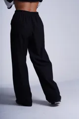 Pantalón de corte amplio y tiro alto, color beige, con elástico en la cintura trasera, pinzas frontales marcadas y bolsillos laterales.