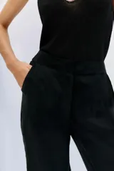 Pantalón palazzo negro de tiro alto, confeccionado en cupro y viscosa, con bolsillos diagonales laterales, bolsillos ojal falsos en la espalda y cierre lateral invisible.